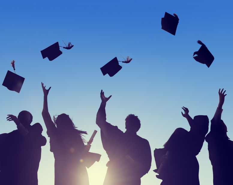 Silhouettes of university graduates tossing their caps into the air